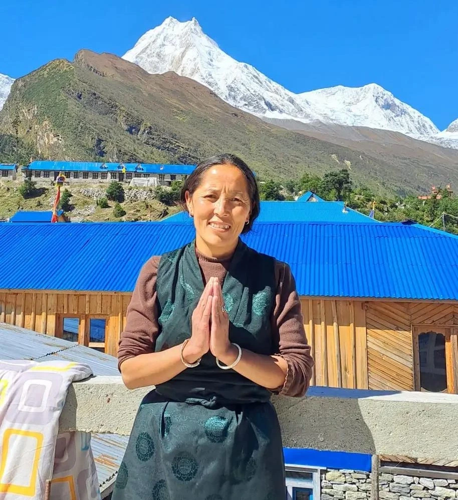 Local woman greeting Namaste with Mount Manaslu in background during Manaslu Circuit Trek Nepal